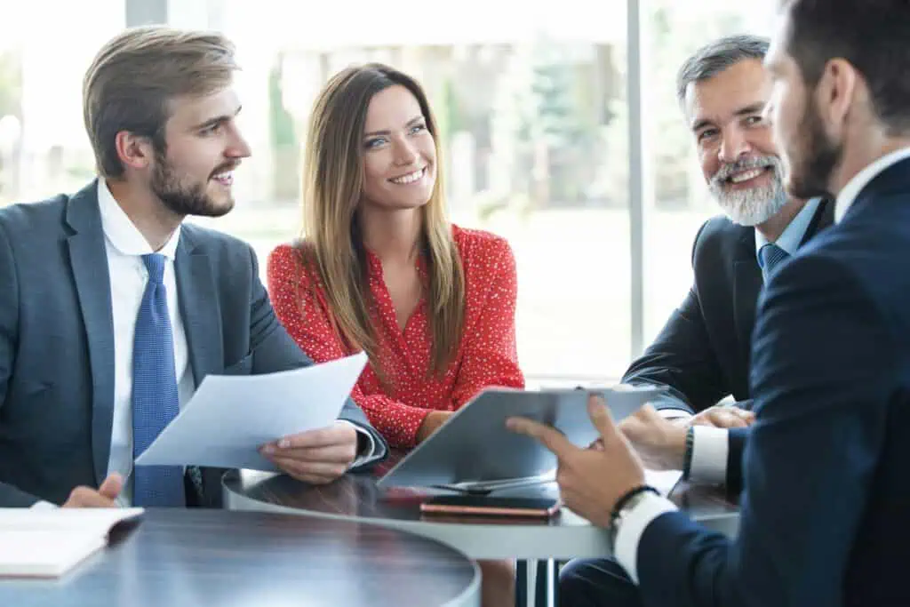 Personen und Berater im professionellen Beratungsgespräch am Besprechungstisch bei der Durchsicht von Unterlagen zur Bewertung von Geldanlagen.